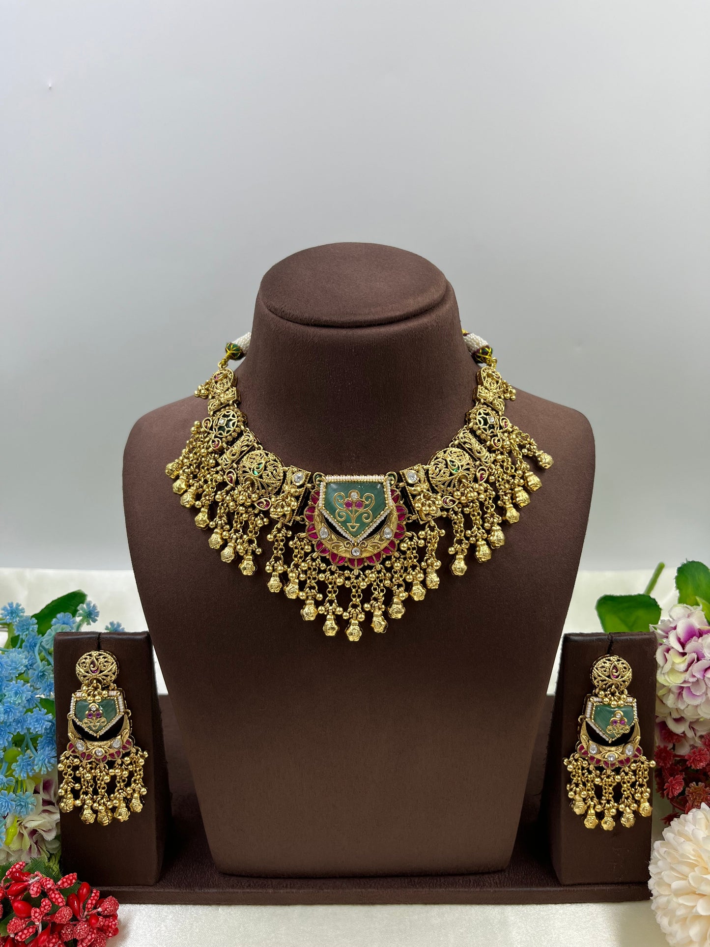 Gold necklace and earrings set on a brown mannequin with a gray background