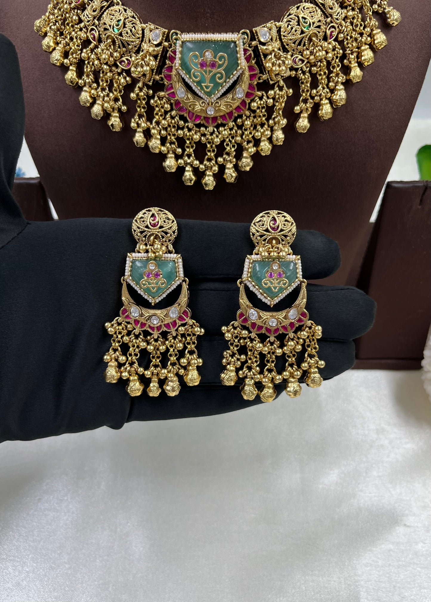 Gold jewelry set with earrings and a necklace on a mannequin.